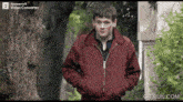 a man in a red jacket is standing in front of a tree with a powersoft video converter on the bottom of the screen