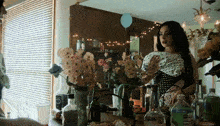 a woman is standing in front of a table full of bottles and flowers including a bottle of aquafina water