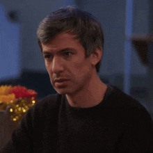 a man in a black sweater is looking at something