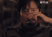 a man is holding a glass of whiskey and making a funny face .