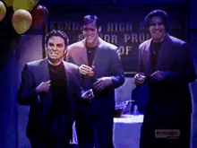 three men are dancing in front of a kennedy high school sign