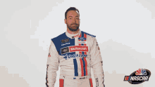 a man in a motorcraft quick lane racing suit stands in front of a nascar logo