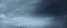 a dark cloudy sky with a few trees in the distance