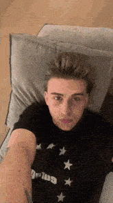 a young man is laying on a couch wearing a t-shirt that says gnatus
