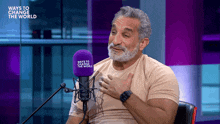 a man sitting in front of a microphone that says ways to change the world on it
