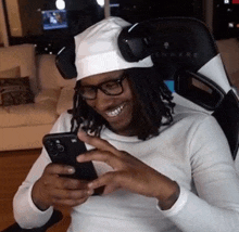 a man wearing a white hat and headphones is looking at his cell phone