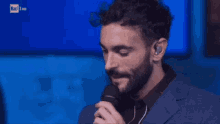 a man with a beard is holding a microphone in his hand .