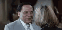 a man in a suit and tie is smiling at a woman in a black jacket .