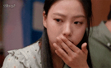 a young woman is covering her mouth with her hand .