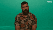 a man with a beard is laughing in front of a green background that says omaha