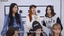 a group of young women are standing in front of a sign that says welcome to my world