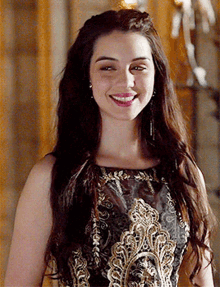 a woman in a black and gold dress is smiling for the camera
