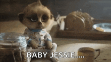 a meerkat doll is sitting on a table next to a cup of coffee and a jar of cookies .