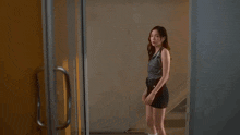 a woman in a black skirt is standing in front of a door