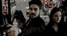 a man with a beard is pointing a gun at a woman