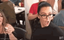 a woman wearing glasses is sitting at a table with a group of people .
