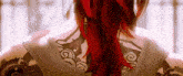 a woman with red hair and a tattoo on her back is standing in front of a window .