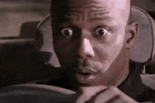 a man with a surprised look on his face is sitting in a car .