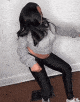 a woman in a gray sweatshirt and black leggings is dancing in a room .