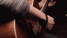 a man is playing an acoustic guitar with a watch on his wrist .