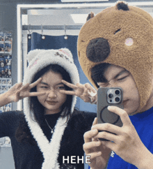 a man wearing a bear hat takes a picture of a woman wearing a cat hat with the word hene below them