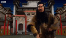 a man with a beard and glasses is dancing in front of a temple .