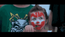a little girl with a clown face painted on her face is brushing her teeth