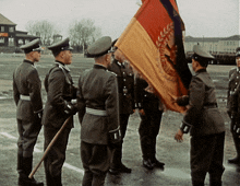 a group of men in military uniforms are holding a flag that says ' deutsche reichsarmee ' on it