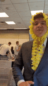 a man in a suit is wearing a yellow lei around his neck