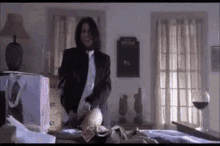 a man in a suit and tie is standing on a bed in a living room .