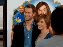 a man and woman are posing for a picture in front of a poster of jesus