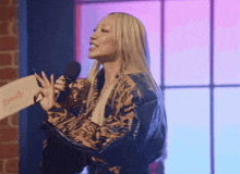 a woman in a leopard print jacket is speaking into a microphone while holding a piece of paper that says butterfly