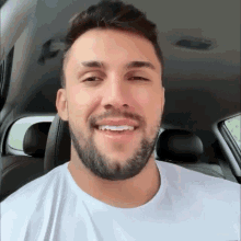 a man with a beard wearing a white shirt is smiling