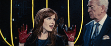 a man and a woman are standing next to each other and the woman is wearing red gloves
