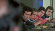 a group of men sitting at a table eating food
