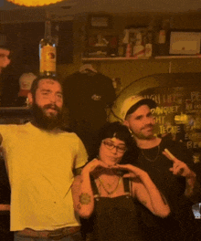 a man with a tattoo on his forehead stands next to a woman and a man with a bottle of tecate on his head