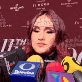 a woman with red hair is surrounded by microphones and a sign that says el moro