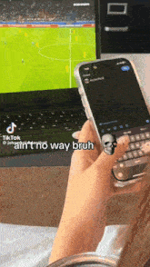 a person holding a cell phone with a skull ring on it