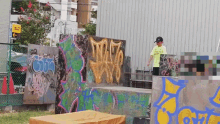 a man stands in front of a wall that has graffiti on it including the letters tmzf