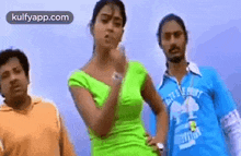 a woman in a green top is dancing with two men in blue shirts .