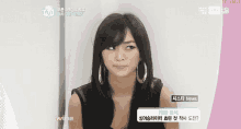 a woman wearing hoop earrings and a black tank top is on a tv screen that says mnet