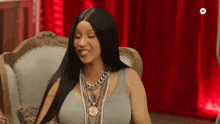 a woman is sitting in a chair wearing a lot of necklaces and a wig .