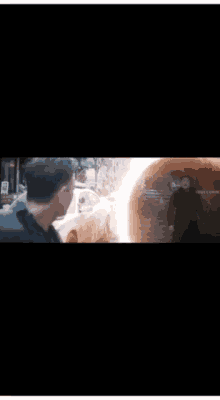 a man in a blue shirt is standing in front of a car that is on fire