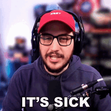 a man wearing headphones and a red hat says it 's sick in front of a microphone