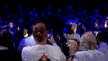 a crowd of people are gathered in a dark room with a sign behind them that says " why should we care "