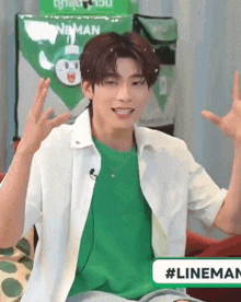a man wearing a green shirt and a white shirt is sitting in front of a green bag .
