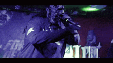 a man in a mask is singing into a microphone in front of a sign that says ' at pm '