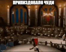a man is doing a trick on a stage in front of a crowd in a large room .