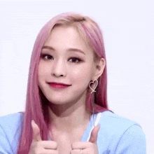 a woman with pink hair is giving a thumbs up .