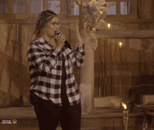 a woman in a plaid shirt sings into a microphone in front of a youtube logo